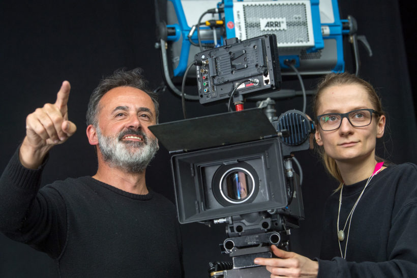 Beitragsbild Berlinale Talents: Ein Mamm mit grauem Bart und eine junge Frau mit Brille stehen an einer Filmkamera.